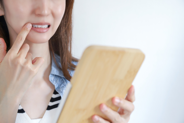 手鏡で歯ぐきを確かめる女性